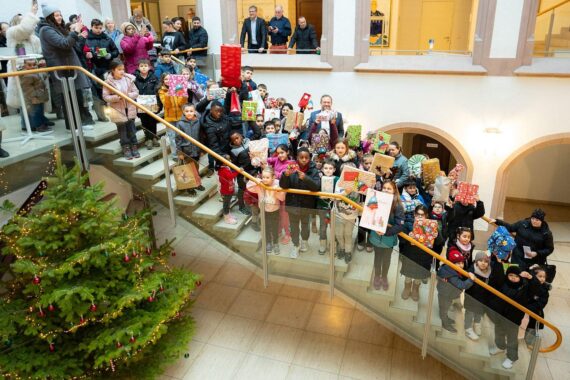 Festliche Übergabe von Geschenken an Kinder beim Wunschbaum-Event im Rathaus Ulm.
