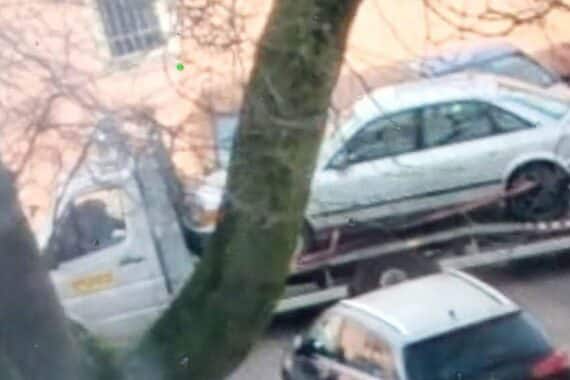 Abschleppwagen mit gestohlenem Audi in einem Hinterhof, Polizeibeamte ermitteln.