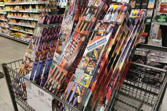 Ein Verkaufsstand für Feuerwerk mit feiernden Menschen in der Silvesternacht.