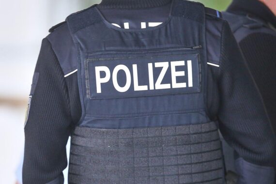 Ein Polizist untersucht eine Grünfläche, während eine Leiche entdeckt wird. Traurige Szenario.
