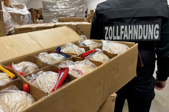 Kugelbomben und beschlagnahmte Pyrotechnik auf einem Tisch, Zollbeamte im Hintergrund.