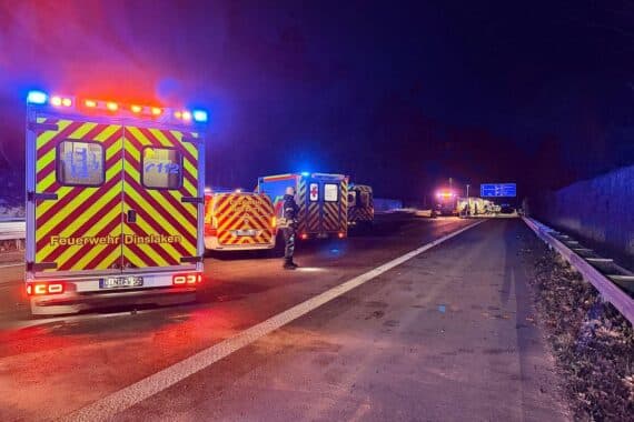 Rettungsfahrzeuge und Feuerwehrpersonal bei einem schweren Verkehrsunfall auf Autobahn. Verwundete werden versorgt.
