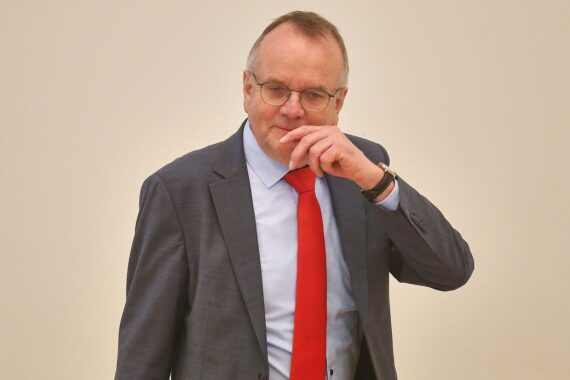 Drei Politiker stehen im Vordergrund, während die politische Lage in Brandenburg diskutiert wird.