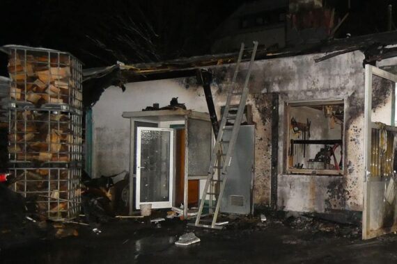Abgebrannte Lagerhalle auf Firmengelände, Feuerwehr im Einsatz, große Zerstörung sichtbar.