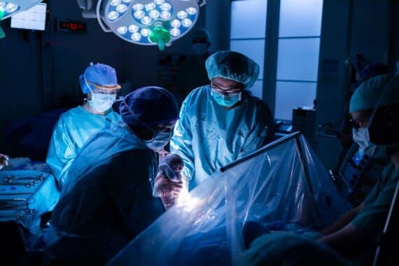 Neugeborenes wird sanft aus dem Mutterleib gehoben, Mutter erlebt Kaiserschnitt bewusst.