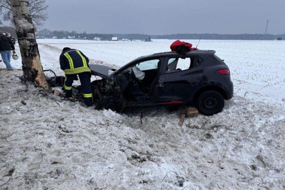 Unfallfahrzeug am Baum, Feuerwehr im Einsatz, Rettungskräfte befreien eingeschlossene Fahrerin.