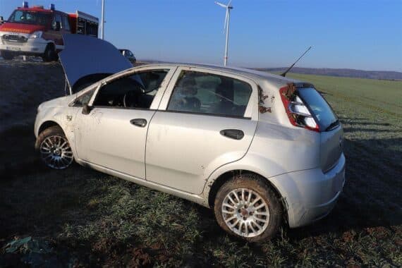 Unfallauto auf Acker, Polizei vor Ort, Fahrerin verletzt, Fiat Punto nicht fahrbereit.