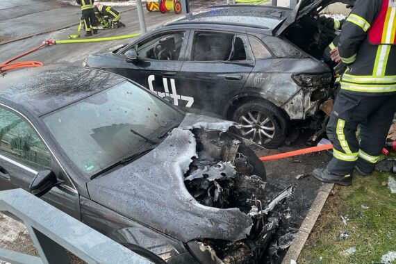 Brennende Autos vor Mehrfamilienhaus, Feuerwehr im Einsatz, Brandursache unklar, keine Verletzten.