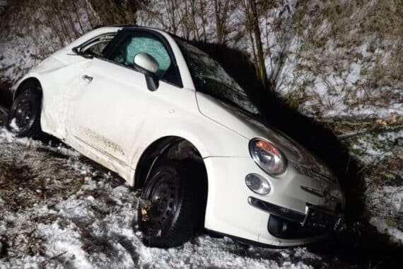 Verunfalltes Fahrzeug im Straßengraben mit Feuerwehr und Rettungsdienst am Einsatzort.