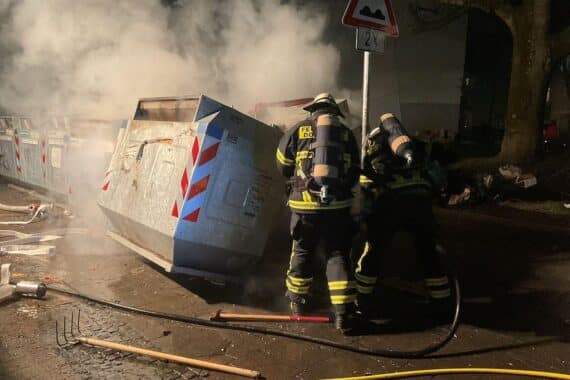 Feuerwehr löscht brennenden Papiercontainer in Dortmund während Silvesterfeuerwerk-Einsätzen.