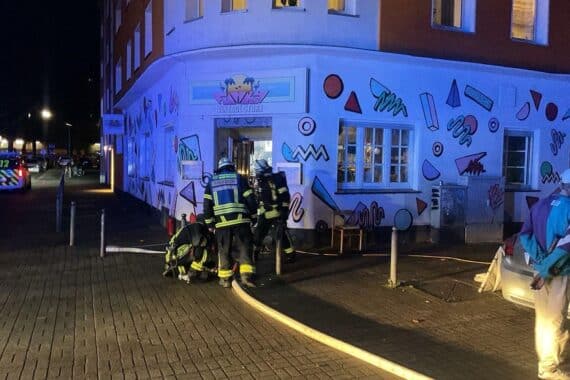 Feuerwehrleute bei Einsatz im Vintage-Bekleidungsgeschäft zur Kontrolle eines Brandes.