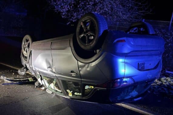 Verunfallter PKW auf dem Dach, Polizei im Einsatz, unkooperative Jugendliche, Unfallstelle in Wiehl.