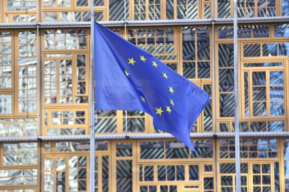 EU-Fahnen und politische Akteure symbolisieren die Dringlichkeit für Veränderungen in Europa.