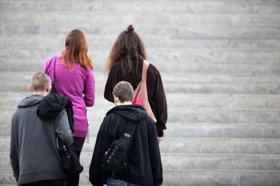 Vier junge Menschen auf einer Treppe, symbolisieren Zusammenarbeit und Gemeinsinn in sozialen Anliegen.