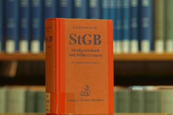Justizminister fordert neue Mordmerkmale für Femizid, symbolisiert durch das Strafgesetzbuch in Bibliothek.