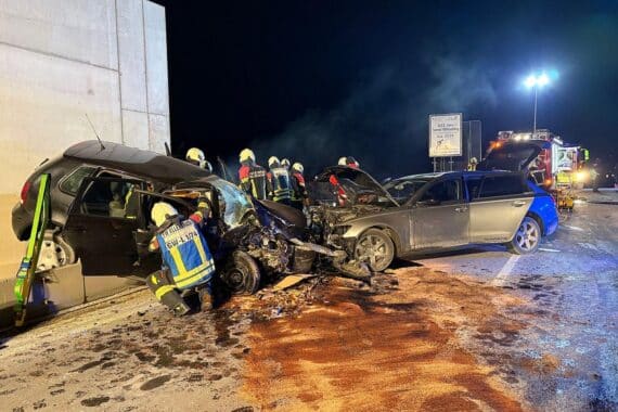 Zwei stark beschädigte Autos nach schwerem Unfall, Rettungskräfte befreien eingeklemmte Person.
