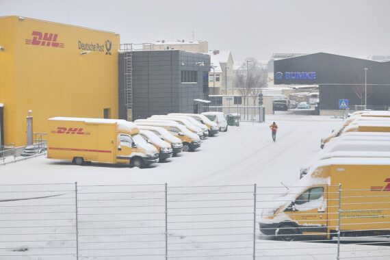 DHL-Zustellbasis mit Zusteller, Werbung für sichere QR-Codes und Informationen zu Betrugsmaschen.