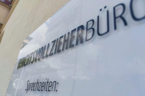 Gerichtsvollzieher bei der Arbeit, Umgeben von unzureichender Schutzausrüstung und verzögerten Beschaffungen.