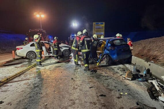 Unfallstelle mit Fahrzeugen, Feuerwehr im Einsatz, Rettungskräfte und Einsatzbeleuchtung.