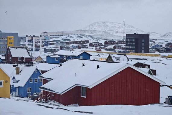 Nuuk, Grönland: eine Stadtansicht am Wasser mit beeindruckenden Bergen und Häusern.