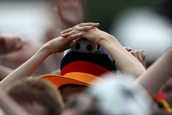 Ein leidenschaftlicher Fußballfan der deutschen Nationalmannschaft im Stadion, jubelnd und mit Fanutensilien.