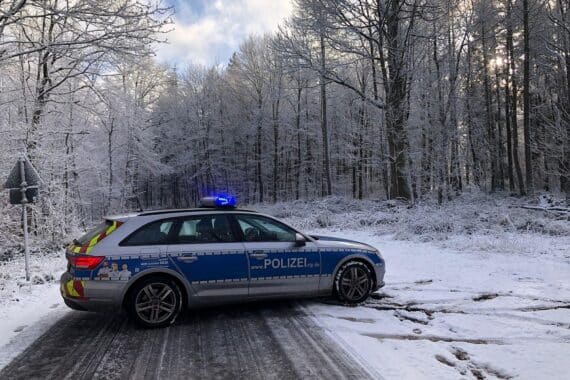 Glatteis verursacht Verkehrsbehinderungen; Polizeiauto und Streudienste im Einsatz zur Verkehrssicherheit.