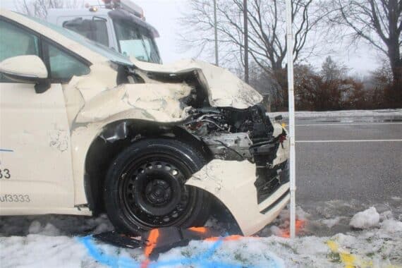 Unfallort mit beschädigten Fahrzeugen: ein Taxi und ein Transporter, Einsatzkräfte helfen Verletzten.