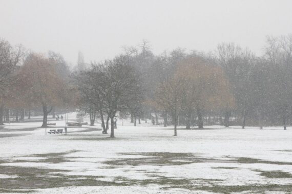 Schneebedeckte Landschaft mit grauem Himmel, Betonung auf Frost und glatte Straßen in NRW.