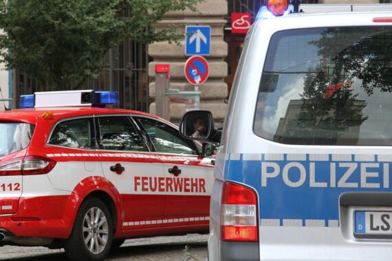 Rettungsmaßnahmen der Feuerwehr nach Wohnhausbrand, Polizei sichert den Einsatzort, traurige Stimmung.