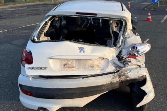 Zwei verunfallte Autos auf der Straße, Polizei und Abschleppwagen sind sichtbar.