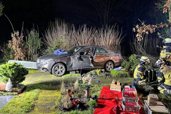 Ein Auto auf einem Friedhof, Feuerwehrleute retten verletzten Fahrer aus der eingeschlossenen Fahrertür.