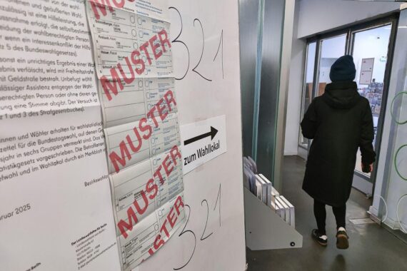 Wahllokal während der Bundestagswahl: Bürger stimmen ab, Wahlurne und Wahlkabinen sichtbar.