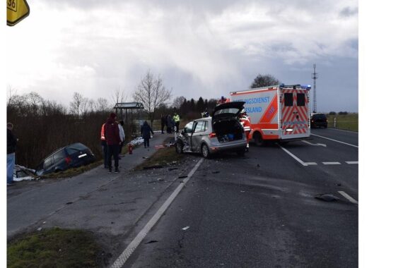 Unfallstelle mit beschädigten Fahrzeugen, Polizei und Rettungskräften, Verletzte werden versorgt.
