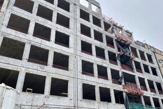 Baustelle mit Bauarbeitern, Kranen und neu errichteten Wohngebäuden symbolisiert Bauboom in Deutschland 2025.