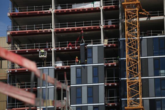 Baustelle mit Bauarbeitern und Materialien, Symbol für den aktuellen Wohnungsbau und Veränderungen.
