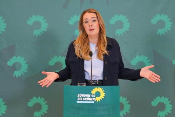 Katharina Dröge diskutiert rechtliche Schritte gegen Bundeshaushalt, symbolisiert durch eine Gerichtsbank.