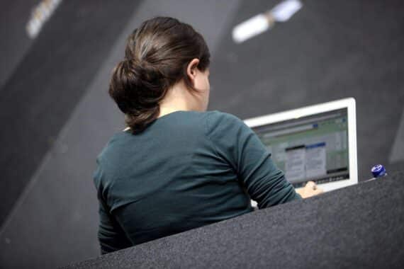 Eine Computer-Nutzerin arbeitet an einem digitalen Gerät, symbolisiert moderne Technologie und digitale Abhängigkeiten.