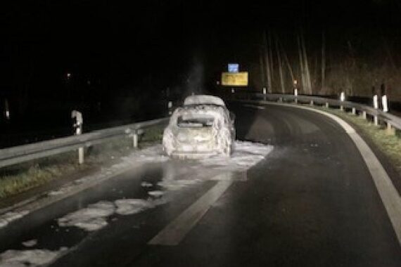PKW brennt lichterloh an Autobahn, Feuerwehr löscht Feuer, Fahrer unversehrt, erheblicher Sachschaden.