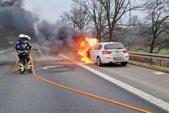 Feuerwehr löscht brennenden Pkw auf Autobahn, lange Staus und Vollsperrung in beide Richtungen.