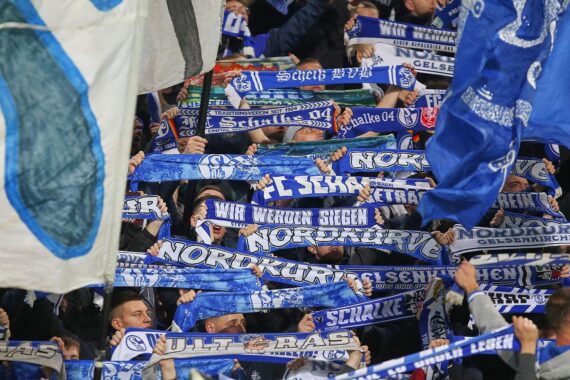 Schalke-Fans im Stadion, jubelnd, während die Polizei den Einsatz überwacht.