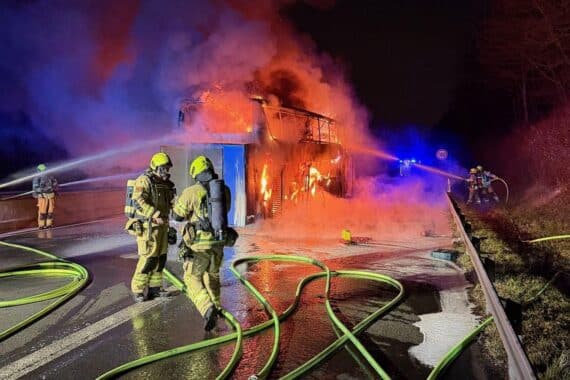Brennender Reisebus auf Autobahn, Feuerwehr im Großeinsatz, Einsatzkräfte, abgesperrte Fahrbahn.
