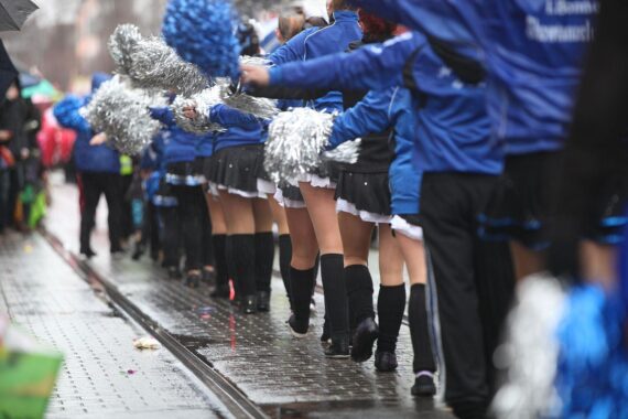 Tanzmariechen mit bunten Kostümen feiern fröhlich im Straßenkarneval, umgeben von Karnevalisten.