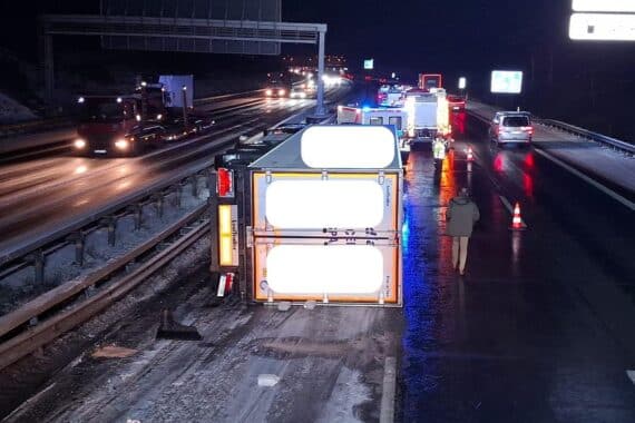 Umgekippter Sattelzug auf der Autobahn, Einsatzkräfte und ausgelaufener Kraftstoff sichtbar.