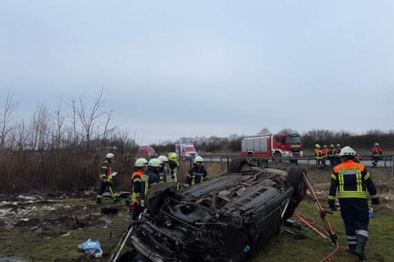 Verunfallter Audi A6 auf Wiese, umgeben von Rettungskräften und Absperrungen.