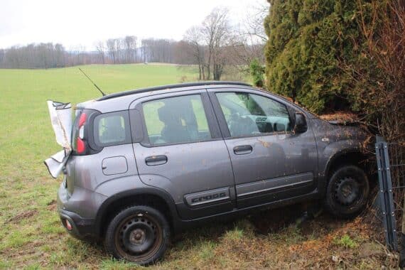 Unfallstelle mit verunfalltem Fiat, umgeben von Strommast und Zaun, Rettungsmaßnahmen im Gange.