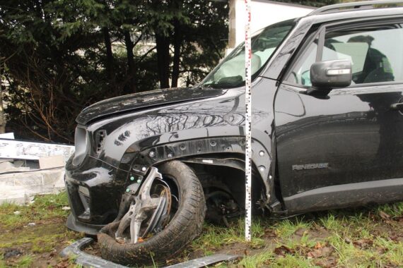 Verunfallter Jeep zwischen Baum und Mauer, Feuerwehr befreit eingeklemmten Fahrer, Unfallstelle gesperrt.