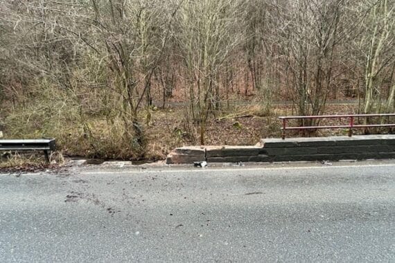 Beschädigte Straßenmauer nach Autounfall, Toyota überschlagen, Polizei vor Ort, Unfallstelle gesperrt.