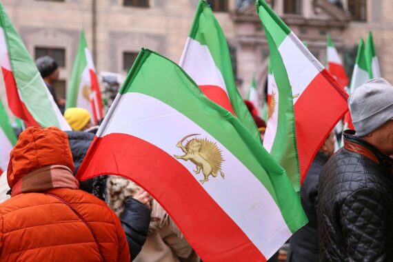 Protestierende Menschen halten Schilder gegen das iranische Regime, symbolisieren Freiheitskampf und Hoffnung.