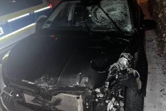 Unfallfahrzeug umgeben von Trümmern, umgestürztes Verkehrsschild, Polizei ermittelt Unfallflucht.