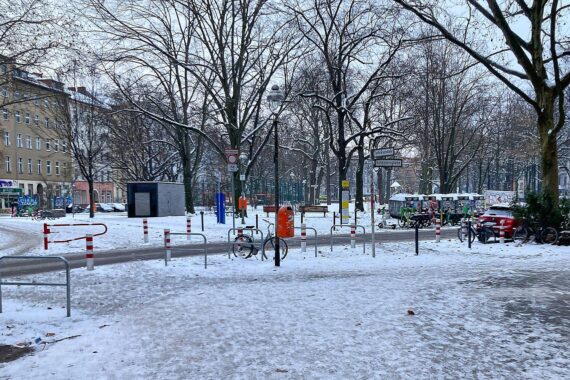 Schneebedeckte Straßen in Berlin, frostige Temperaturen, glatte Gehwege und dunkle Wolken.